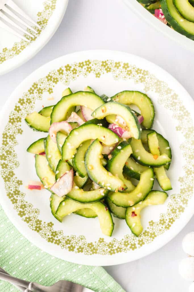 cucumber salad served on a plate with sesame seeds and red onion