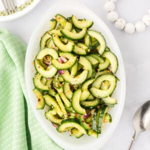 overhead view of cucumber salad in a serving dish with sesame seeds and red onion