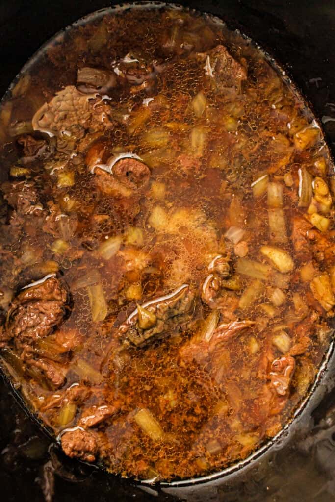 Cooked beef and onions in sauce inside a slow cooker before adding broccoli