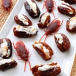 Halloween date cockroaches filled with cream cheese and walnuts and displayed with red plastic roaches