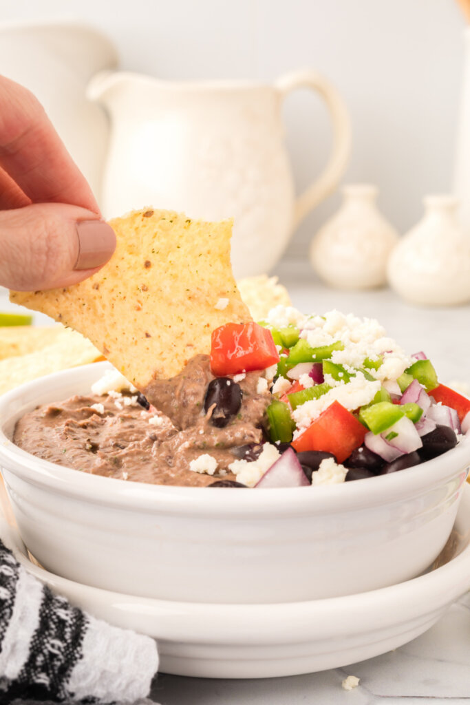 tortilla chip being dipped into black bean hummus