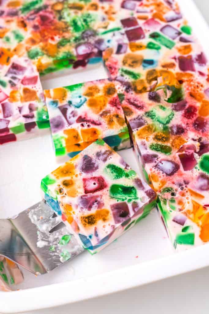 Sliced Broken Glass Jello dessert squares showing colorful gelatin cubes in creamy milk gelatin