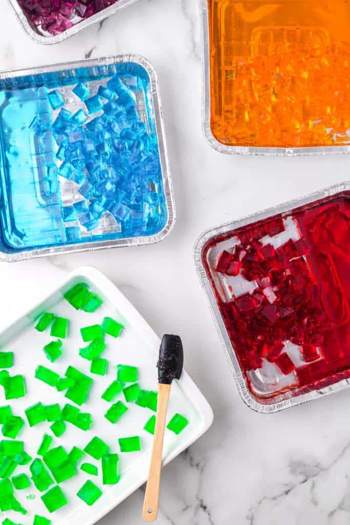 Cubed gelatin pieces for Broken Glass Jello recipe arranged in foil pans and baking dish