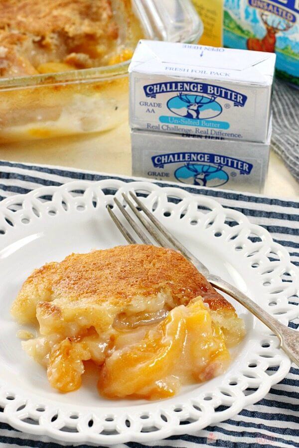 Easy Southern Peach Cobbler on a plate with a fork and two sticks of Challenge Butter.