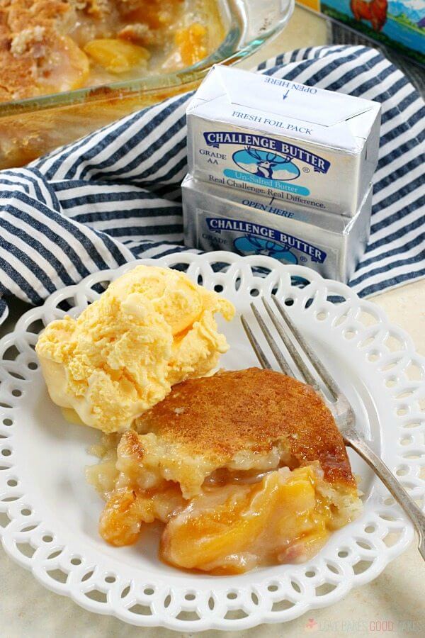 Easy Southern Peach Cobbler on a plate with ice cream and a fork and two cubes of Challenge Butter.