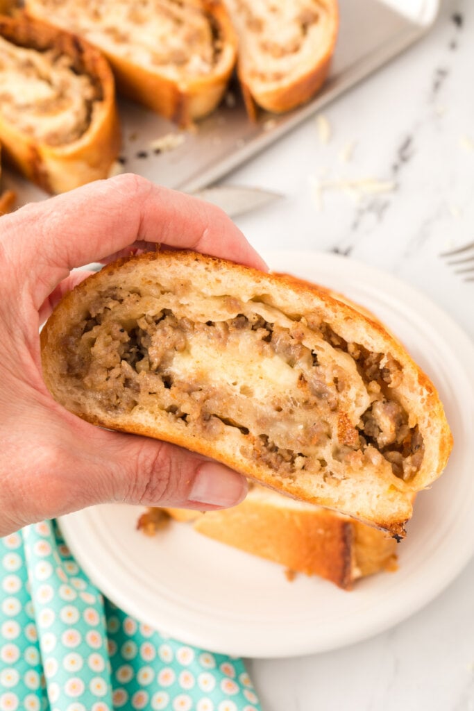 hand holding slice of sausage bread