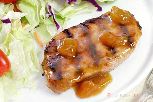 Dijon-Peach Pork Chops on a plate with a green salad close up.