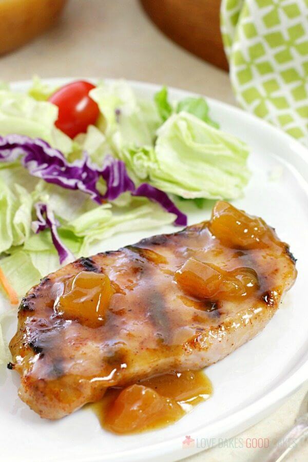 Dijon-Peach Pork Chop on a plate with a green salad.