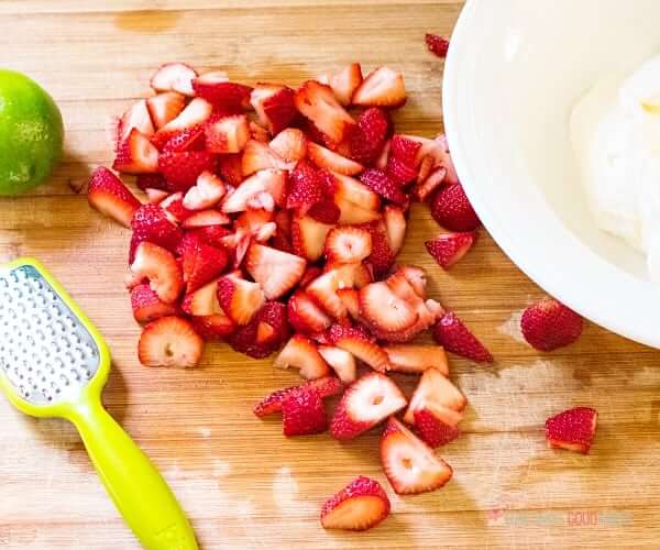 Strawberries sliced a cutting board.