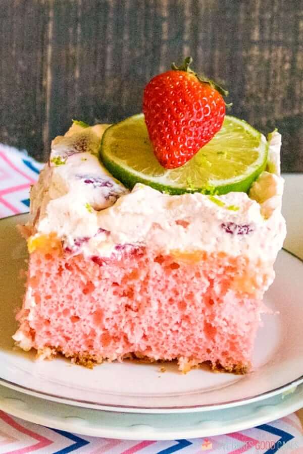 Boozy Strawberry Margarita Poke Cake on a plate with fresh fruit.