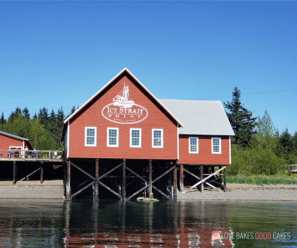 Icy Strait Point building sits on the shoreline with people standing on the deck area.