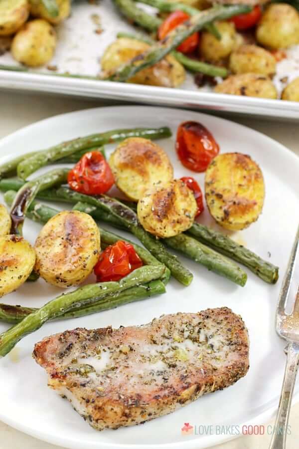 Italian Pork Chop Sheet Pan Dinner on a white plate with a fork.