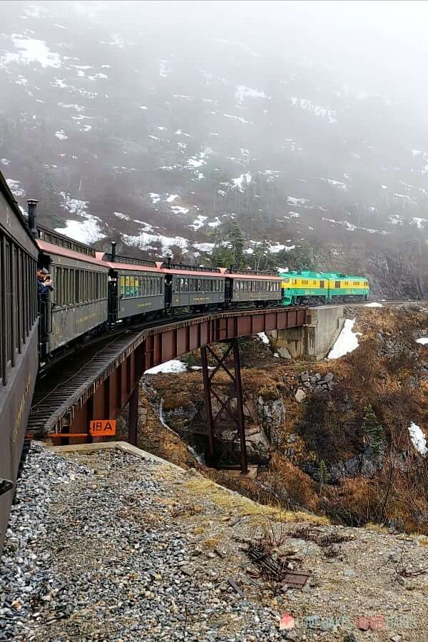 White Pass Railway descending down the mountain over a trestle bridge with snow and fog.