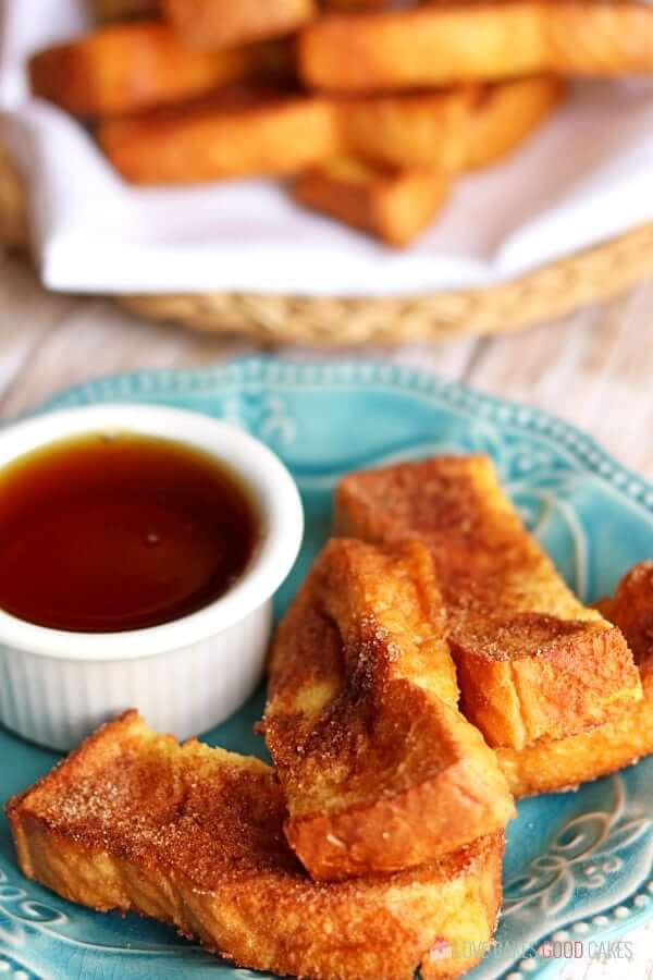 Air Fryer French Toast Sticks on a blue plate with a cup of syrup.