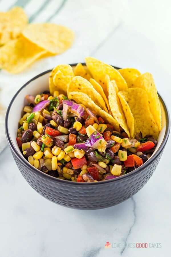 Black Bean and Corn Salsa in a black bowl with tortilla chips.