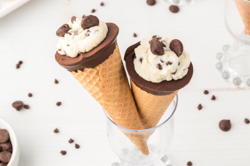 two cannoli cones being held up in a glass