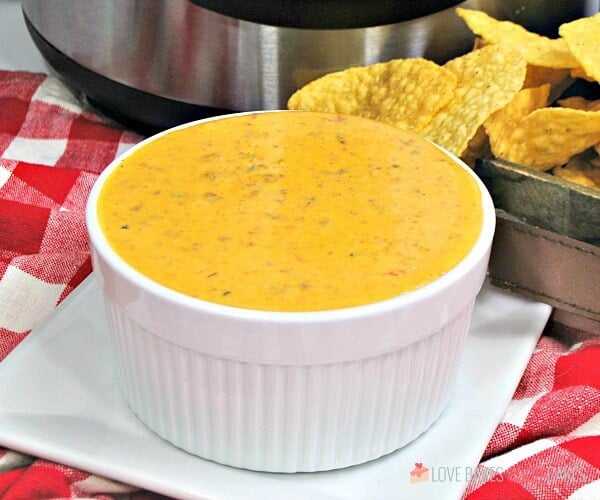 Instant Pot Mexican Queso in a white bowl with tortilla chips.