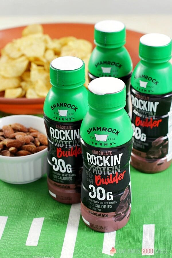 Four bottles of Shamrock chocolate milk with a bowl of tortilla chips and nuts.