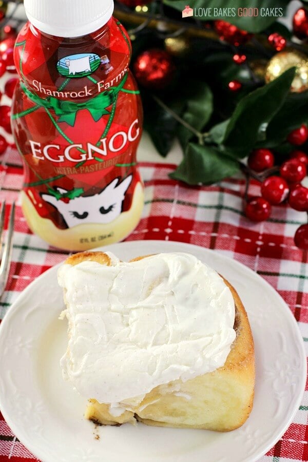 Eggnog Cinnamon Roll on a plate with a bottle of Eggnog.