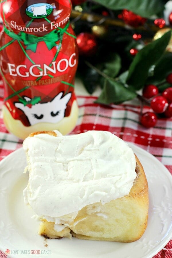 Eggnog Cinnamon Roll on a plate with a bottle of Eggnog close up.