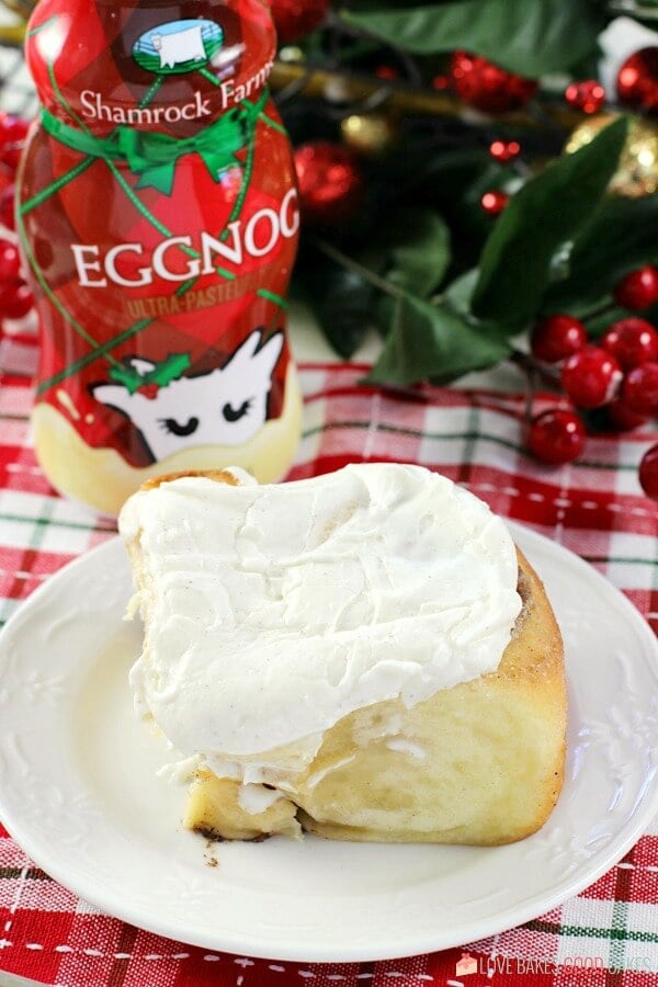 Eggnog Cinnamon Roll on a plate with a bottle of egg nog.