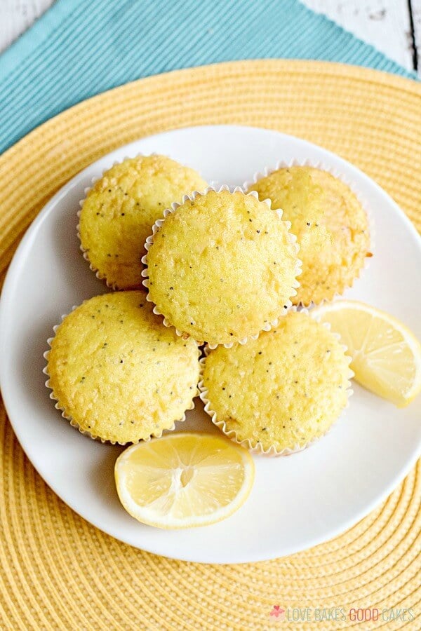 Lemon Poppy Seed Muffins piled up on a plate with fresh lemon wedges.