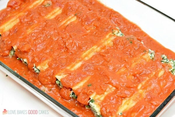 Spinach Ricotta Manicotti covered in red marinara sauce in baking dish