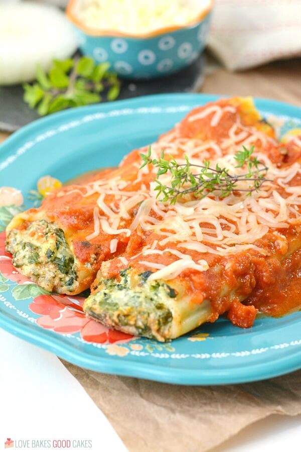 close up of spinach ricottta manicotti on blue plate