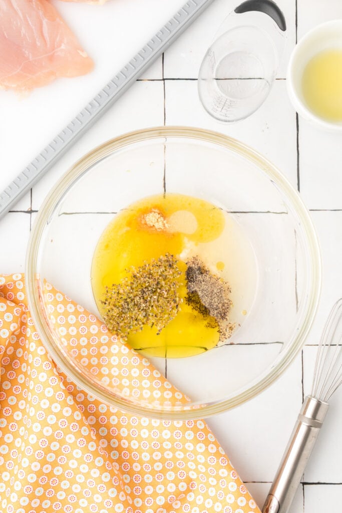 Bowl of marinade ingredients including olive oil, lemon juice, garlic, and seasonings before mixing
