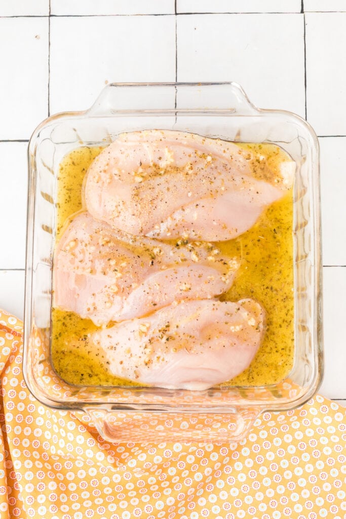 Chicken breasts in a glass baking dish covered with the prepared marinade