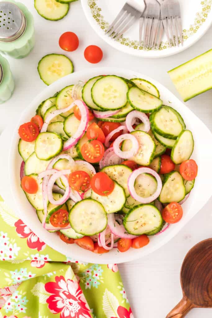 Final salad served in a white bowl with cherry tomatoes and sliced cucumbers
