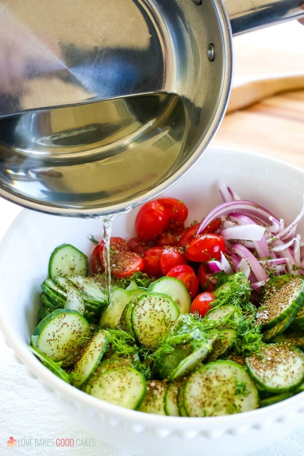 pouring dressing over cucumber salad