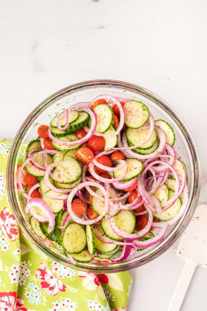Tossed cucumber tomato salad with red onions and herbs in a large glass bowl