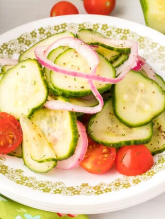 Close-up square image of cucumber tomato salad on a plate with onions and tomatoes