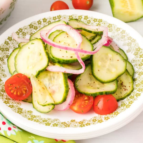 Close-up square image of cucumber tomato salad on a plate with onions and tomatoes