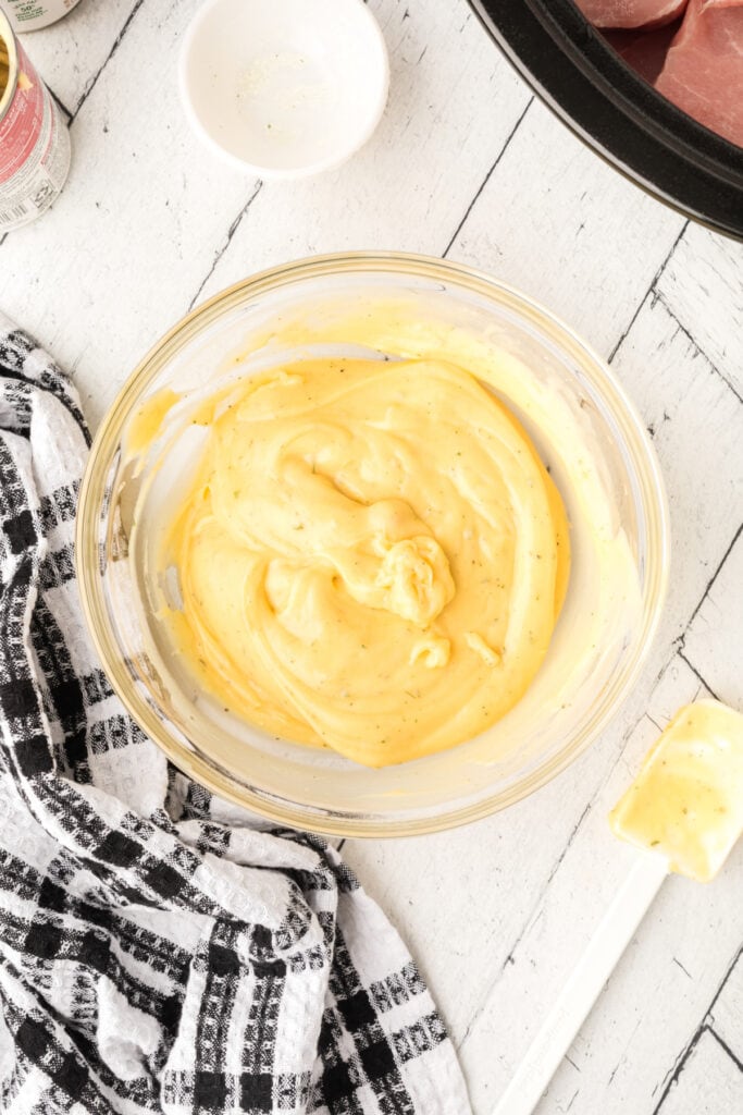 Combined soup and Ranch mixture in a glass bowl with a spatula and black-and-white towel beside it.