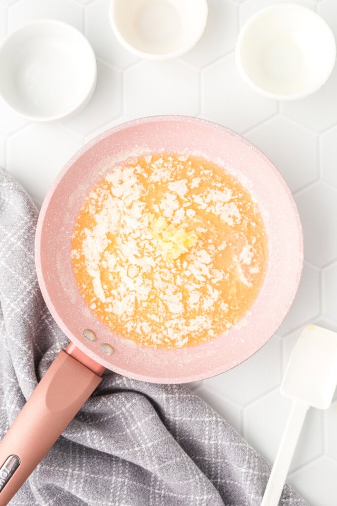 Butter melting in a pink pan on the stovetop.