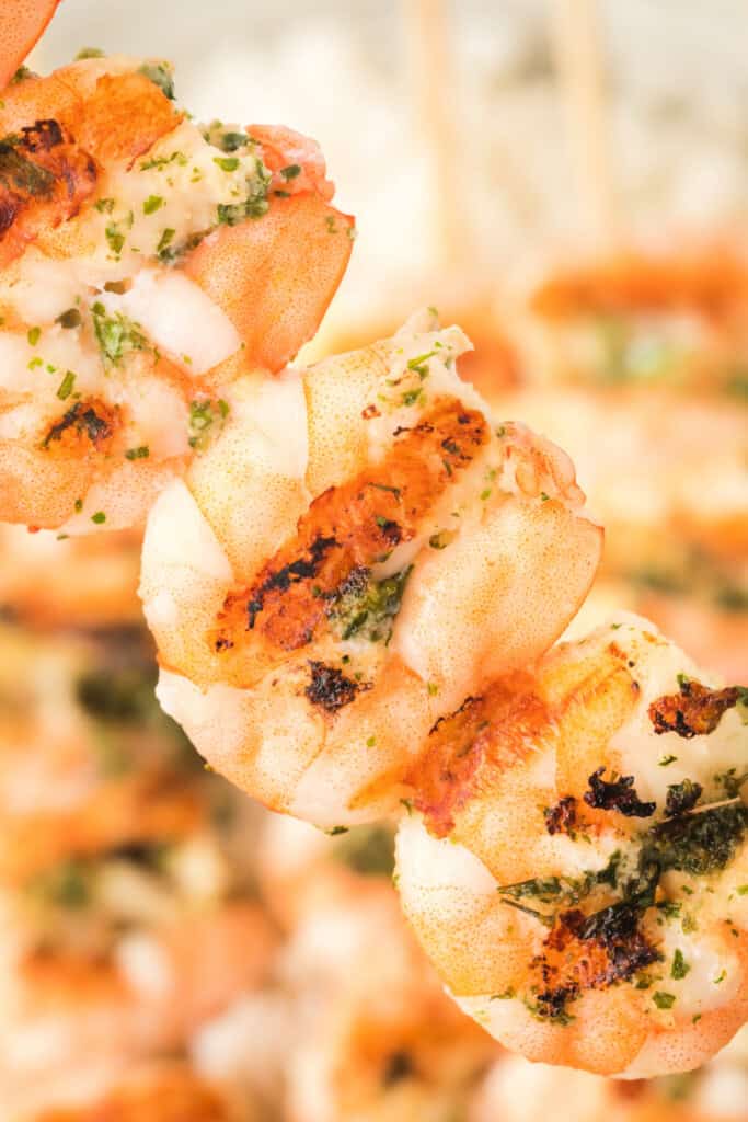Extreme close-up of juicy grilled shrimp showing charred edges and herbs.
