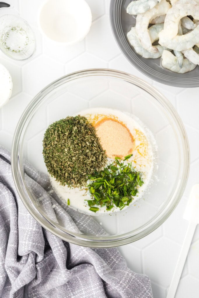 	Dry seasonings and fresh chives added to melted butter in a glass bowl.