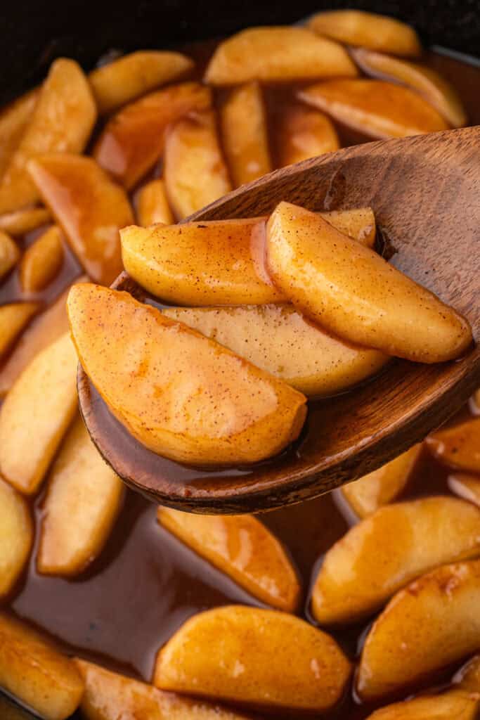 Spoon lifting tender cinnamon fried apples coated in buttery syrup.