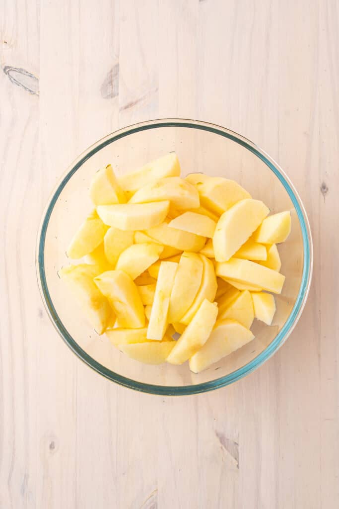 Peeled apple slices tossed with lemon juice before cooking.