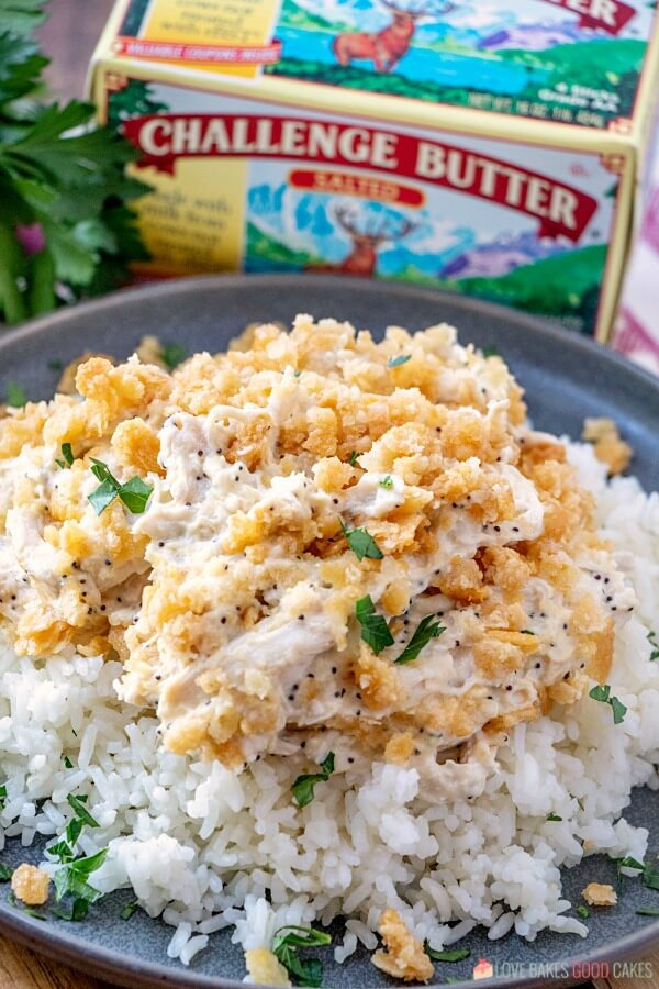 This Poppy Seed Chicken Casserole has a creamy poppy seed sauce filled with shredded chicken and topped with a rich buttery cracker crumb crust. Poppy Seed Chicken Casserole on a plate with a package of Challenge Butter.