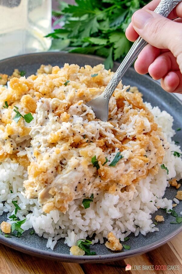 This Poppy Seed Chicken Casserole has a creamy poppy seed sauce filled with shredded chicken and topped with a rich buttery cracker crumb crust. Easy dinner idea - Poppy Seed Chicken Casserole on a plate with a fork.