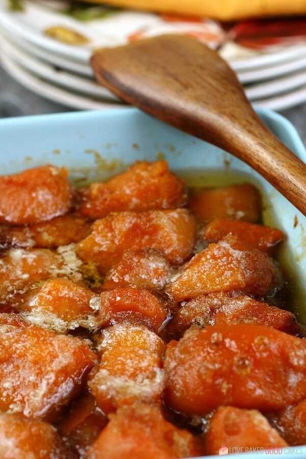 Candied Yams in a blue dish with a wooden spoon.