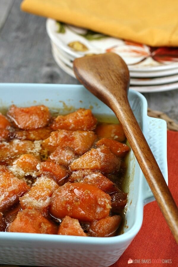 Candied Yams in a blue bowl with a wooden spoon.