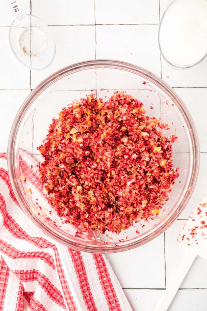 Mixed cranberry relish showing blended cranberries, apples, oranges, and walnuts in a clear glass bowl.