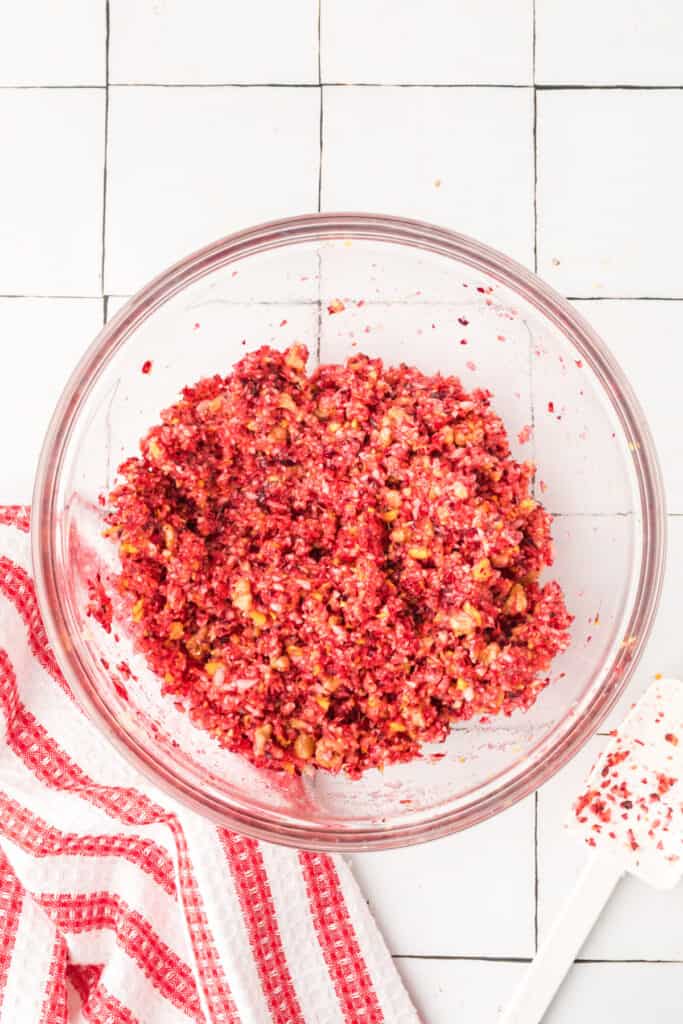 Fully mixed cranberry relish showing bright red color and evenly combined texture in a glass bowl.
