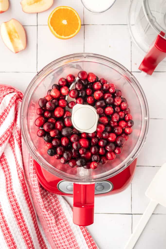Finely chopped orange pieces inside the red food processor, showing a bright yellow-orange mixture.