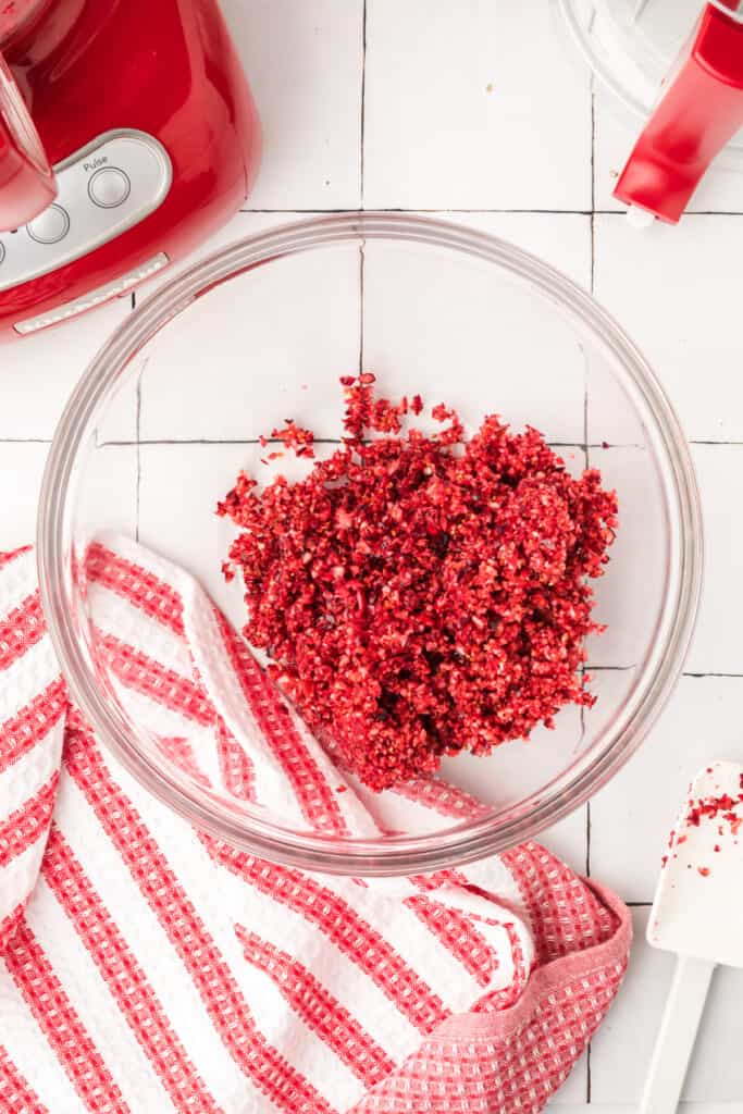 Finely chopped orange pieces inside the red food processor, showing a bright yellow-orange mixture.