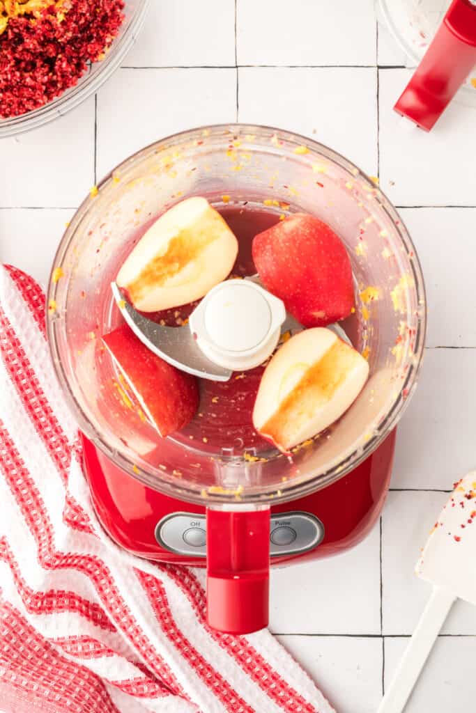 Apple quarters added to the food processor bowl for the next chopping step in the cranberry relish process.